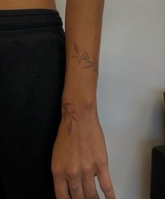 a woman's hand with a small tattoo on her left wrist and the other arm