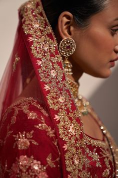 a woman wearing a red bridal gown with gold embroidery on the neck and shoulders