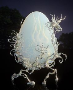 an intricately designed glass egg is lit up in the night sky with its legs spread out