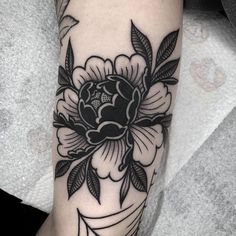 a black and white flower tattoo on the left leg, with an arrow in the middle