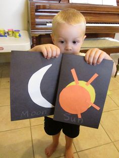 a young boy holding up two books with the words moon and sun on them