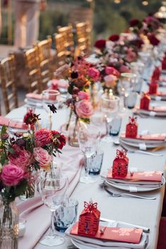 a long table is set with place settings and flowers in vases on the tables