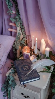 two books are sitting on top of a dresser with candles and greenery around it