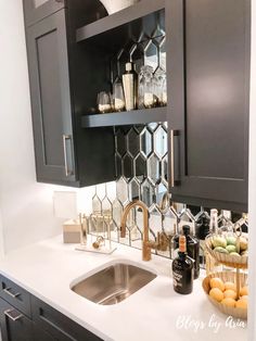 a kitchen with black cabinets and white counter tops, an open shelf above the sink