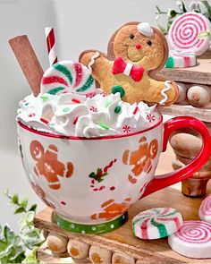 a cup filled with marshmallows, candy canes and gingerbread cookies