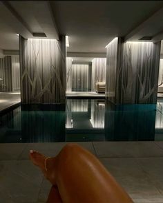 a person's feet in front of a swimming pool with curtains on the walls