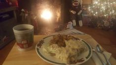 a plate with mashed potatoes on it next to a cup of coffee and an ornament