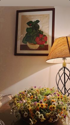 a lamp is next to a potted plant on a table with flowers in it