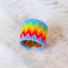 a multicolored beaded bracelet with sunglasses on it's side sitting on top of a white surface