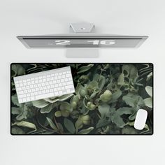 a computer keyboard and mouse sitting on top of a mouse pad next to a plant