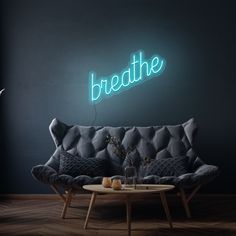 a living room with a couch, coffee table and neon sign on the wall above it