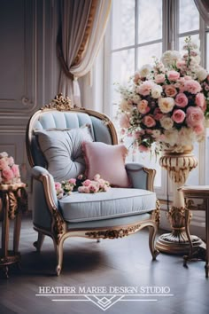 a blue chair sitting in front of a window next to a vase filled with flowers