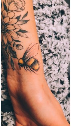 a small tattoo on the foot of a woman with a bee and flower in it