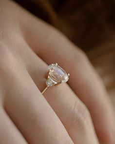 a woman's hand holding an engagement ring with two pear shaped diamonds on it