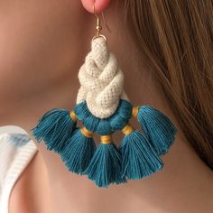 a woman wearing blue and white earrings with tassels