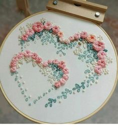 a heart made out of flowers and pearls on a white embroidery hoop with a wooden frame