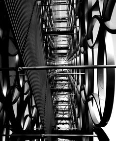 black and white photograph of an abstract structure with many circular metal objects hanging from it's sides