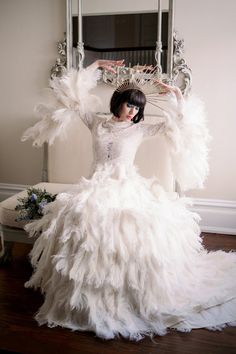 a woman in a white dress with feathers on it