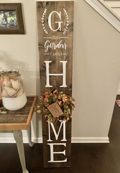 a wooden sign with the word home painted on it next to a potted plant