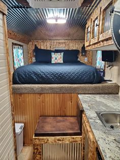 the interior of a tiny house with a bed and sink in it, as well as a kitchenette