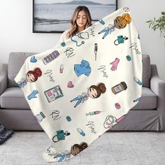 a woman holding up a blanket with nurse icons on it in front of a couch