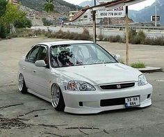 a white car parked in front of a gas station with mountains in the back ground