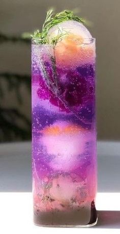 a tall glass filled with purple liquid and green sprigs