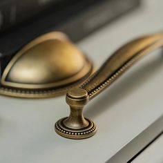 a close up of a brass handle on a white cabinet