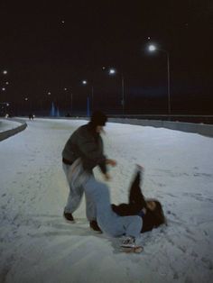 two people are playing in the snow at night