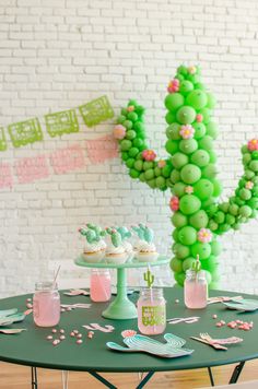 a cactus themed birthday party with green balloons and pink flowers on the top of it