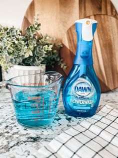 a bottle of dawn powerwash next to a measuring cup and bowl on a counter