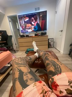 a person with tattoos on their legs watching tv