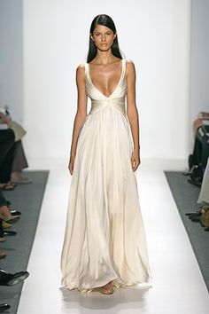 a woman walking down a runway wearing a white dress