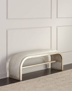 a white bench sitting on top of a hard wood floor next to a wall with paneling