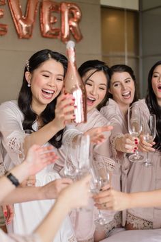 a group of women standing around each other holding wine glasses