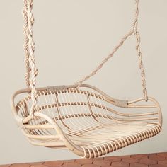 a white rattan swing hanging from a rope