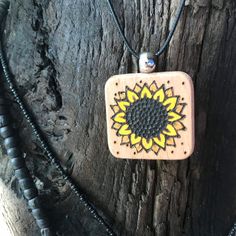 a wooden necklace with a yellow and black sunflower on it's back end