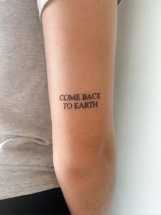 a woman with a tattoo on her arm that says come back to earth in black ink