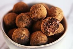 a white bowl filled with chocolate truffles on top of a table