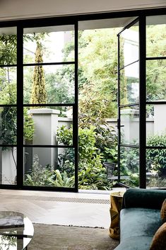 a living room filled with furniture and lots of glass doors that look out onto a garden