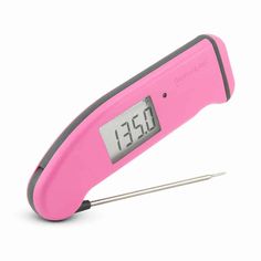 a pink digital thermometer with a needle in it's center and an alarm clock on top