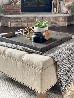 a living room with a couch, coffee table and fireplace in the background that has a potted plant on it