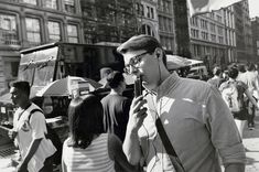 a black and white photo of a man standing in the street with headphones on