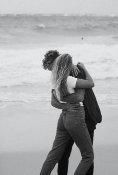 black and white photograph of two people hugging on the beach