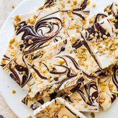 a white plate topped with pieces of cake covered in frosting and chocolate toppings