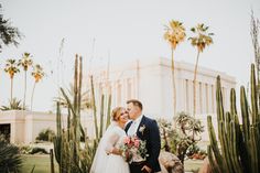 a bride and groom standing in front of some cacti