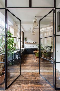 an open glass door leading to a kitchen and dining area with potted plants on the counter