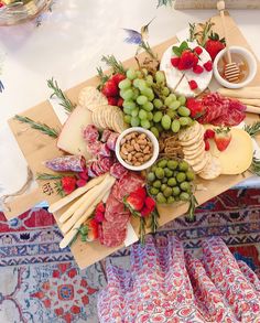 a cheese platter with grapes, strawberries, nuts and meats on it