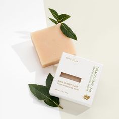 a bar of soap sitting on top of a white surface next to a green leaf