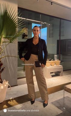 a woman standing next to a plant in front of a glass wall with an advertisement on it